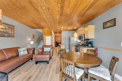 a kitchen and living room with a wooden ceiling at Lakefront Oasis - Adorable lakefront cabin with a private beach! in Big Bear Lake