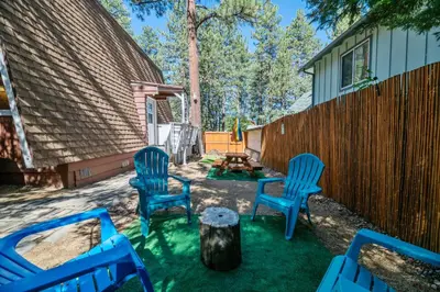 a backyard with blue chairs and a table and a fence at A Beary Happy Cabin - Charming gambrel style home within minutes of the Lake and The Village in Big Bear Lake