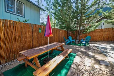 a picnic table with a red umbrella in a backyard at A Beary Happy Cabin - Charming gambrel style home within minutes of the Lake and The Village in Big Bear Lake