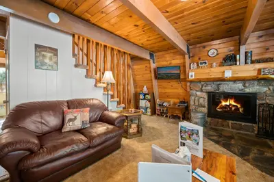 a living room with a leather couch and a fireplace at A Beary Happy Cabin - Charming gambrel style home within minutes of the Lake and The Village in Big Bear Lake
