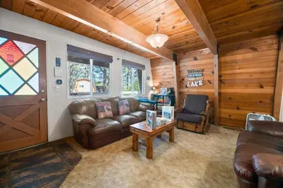 a living room with a leather couch and a table at A Beary Happy Cabin - Charming gambrel style home within minutes of the Lake and The Village in Big Bear Lake
