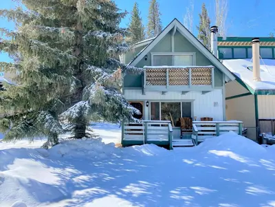 a house with a porch in the snow at Village Hideaway - Perfectly cozy cabin with a beautiful location, walking distance to everything! in Big Bear Lake