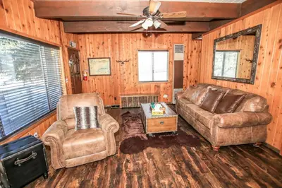 a living room with leather furniture and a ceiling fan at Village Hideaway - Perfectly cozy cabin with a beautiful location, walking distance to everything! in Big Bear Lake