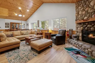 a living room with a large stone fireplace at Treetop Bearadise - Best mountain living in a nicely furnished and decorated home in Big Bear Lake