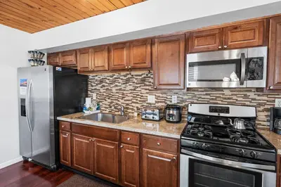 a kitchen with wooden cabinets and a stainless steel appliances at The Rock House - Walk to Big Bear Snow Play! Walk to Oktoberfest! Perfect weekend getaway! in Big Bear City