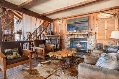 a living room with a table and a fireplace at The Voges' Lake House - Amazing lake front house with a beautiful view and game room! in Big Bear Lake