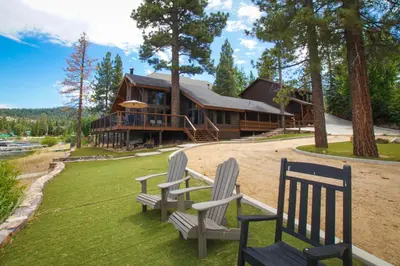 two chairs sitting in the grass in front of a house at The Voges' Lake House - Amazing lake front house with a beautiful view and game room! in Big Bear Lake
