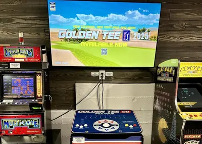 a video game machine and a television on a wall at The Grizzlies Den - Log style cabin located in the desirable Fox Farm area! Games and arcade! in Big Bear Lake