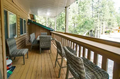 a screened porch with chairs and a table on it at The Grizzlies Den - Log style cabin located in the desirable Fox Farm area! Games and arcade! in Big Bear Lake