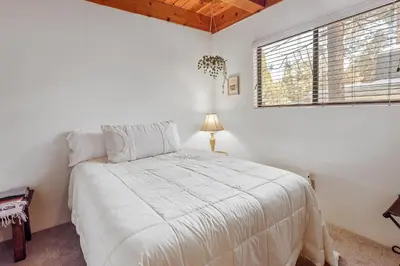 a white bedroom with a bed and a window at The Lakehouse Cabin - Located close to the Lake! Hot Tub, Smart TV, and WiFi! in Big Bear Lake