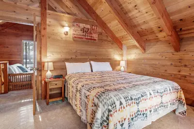 a bedroom with a bed in a log cabin at The Lakehouse Cabin - Located close to the Lake! Hot Tub, Smart TV, and WiFi! in Big Bear Lake