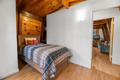 a bedroom with a bed in a room with wooden ceilings at The Cozy Bear Cabin - Updated gambrel with huge outdoor space! Cornhole, Tether ball, Fire pit! in Big Bear Lake