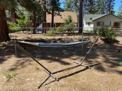 a hammock in a yard in front of a house at The Cozy Bear Cabin - Updated gambrel with huge outdoor space! Cornhole, Tether ball, Fire pit! in Big Bear Lake