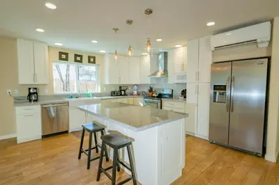 a kitchen with white cabinets and a large island with bar stools at Modern Times - Amazing place with super open concept! Jet tub! in Big Bear Lake