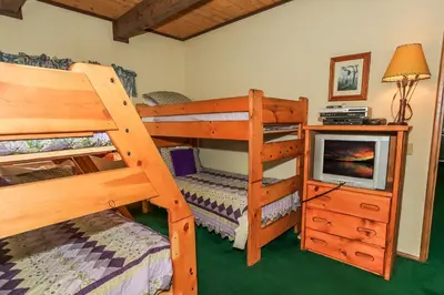 a bedroom with two bunk beds and a television at Summit Adventure - Beautiful, spacious and quiet home! Foosball, pool and poker table! Jet tub! in Big Bear Lake