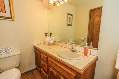 a bathroom with a sink and a toilet and a mirror at Summit Adventure - Beautiful, spacious and quiet home! Foosball, pool and poker table! Jet tub! in Big Bear Lake