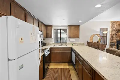 a kitchen with wooden cabinets and a white refrigerator at Summit X-ross Roads - Just a short drive to the Village and the lake with forest views! in Big Bear Lake