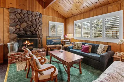 a living room with a couch and a fireplace at Snowridge - Charming classic cabin with a wood burning fireplace and WiFI! in Big Bear City