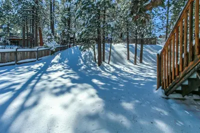 a snow covered path with a fence and trees at Bare Necessities - Comes with a hot tub and a pool table in Big Bear Lake