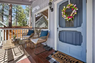 a blue door on a porch with chairs and a wreath at Serenity Knoll - Comfortable, spacious single-level cabin! Newly remodeled! Hot Tub and Pool Table! in Big Bear Lake