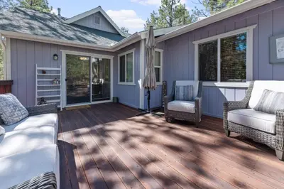 a deck with chairs and tables on a house at Serenity Knoll - Comfortable, spacious single-level cabin! Newly remodeled! Hot Tub and Pool Table! in Big Bear Lake