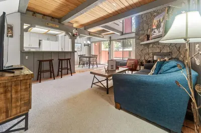 a living room with a blue couch and a kitchen at Ski-In Ski-Out Summit Townhouse- Perfect mountain getaway with views of the forest and Snow Summit! in Big Bear Lake