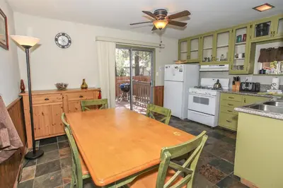 a kitchen with a wooden table and a ceiling fan at Rincon Cabin - Close to the lake with a huge fenced in yard! Hot tub and deck with barbecue! in Big Bear Lake