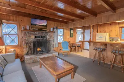 a living room with a stone fireplace and a bar at Sauer Suite - Cozy, rustic cabin walking distance to Holloway's Marina with peek-a-boo lake views! in Big Bear Lake