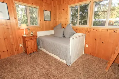 a bedroom with a bed in a wooden room at Owl Cabin - Sierra style cabin located on a quiet road in Fawnskin and backs up to National Forest! in Fawnskin
