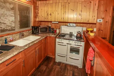 a kitchen with a white stove and a microwave at Owl Cabin - Sierra style cabin located on a quiet road in Fawnskin and backs up to National Forest! in Fawnskin