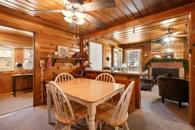 a dining room with a wooden table and chairs at Pine Forest Cabin - Adorable vintage cabin with a cozy wood burning fireplace and foosball table! in Big Bear Lake