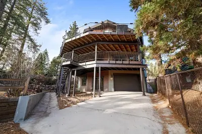a house with a deck on top of it at North Shore Lakefront - Spacious Lakefront with Hot Tub, & Game Room in Fawnskin