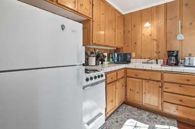 a kitchen with a white refrigerator and wooden cabinets at Oak Nesting - Great chalet style cabin at the end of the street with rustic stone gas log fireplace! in Big Bear Lake