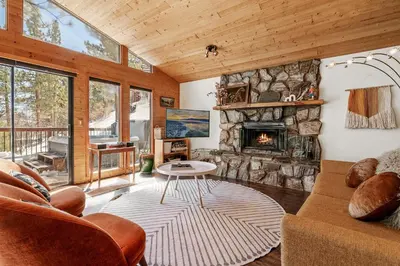 a living room with a stone fireplace and a couch at Nightcap Lodge- HOT TUB WITH BREATHTAKING MOUNTAIN VIEWS! in Fawnskin