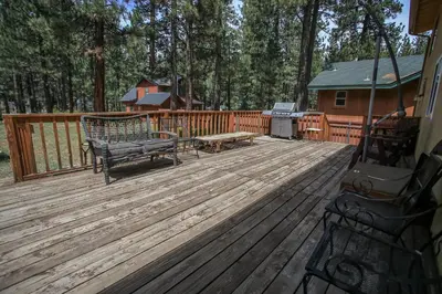 a wooden deck with a bench and a grill at Mountain Fever - Offers a Foosball Table and Barbecue Grill and a large back deck! in Big Bear Lake