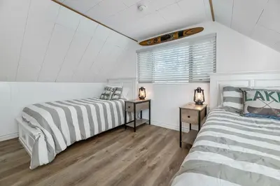 two beds in a room with white walls and wood floors at Boulder Bay Bungalow - Updated mountain retreat with hot tub, game table, and sauna! in Big Bear Lake