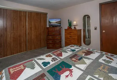 a bedroom with a bed with a quilt on it at Bear 'n Tree - Cozy cabin near the Village in Big Bear Lake