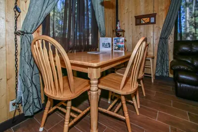 a wooden table with two chairs and a laptop on it at Bear 'n Tree - Cozy cabin near the Village in Big Bear Lake