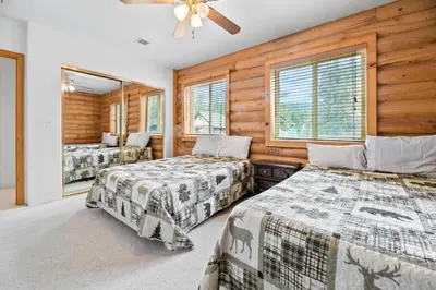 two beds in a room with wooden walls and windows at Bear Bait - Lots of games, televisions, beds, telescope, and 3 bathrooms in Big Bear Lake