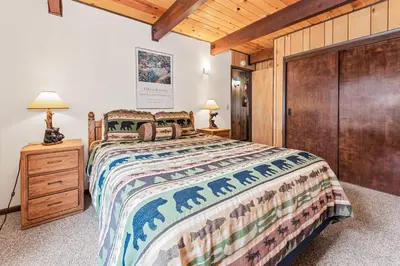 a bedroom with a large bed and a wooden closet at Bear Crossing - Walk to Snow Summit! Visit this charming mountain home compete with foosball table in Big Bear Lake