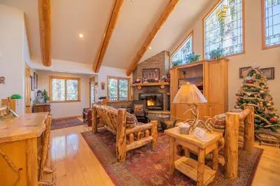 a living room with a fireplace and a christmas tree at Bearfoot Bungalow - Premium and spacious home close to the National Forest and The Village! in Big Bear Lake
