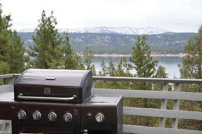 a grill sitting on a table with a view of a lake at Best View - Spacious home with game room, and 180 degree panoramic view of Big Bear Lake! in Fawnskin