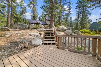 a wooden walkway leading to a cabin in the woods at Boulder Bear - Modern mountain home in a desirable area of Big Bear with peek-a-boo lake views in Big Bear Lake