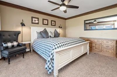 a bedroom with a bed and a black chair at Grand Lakefront Escape - Gorgeous Lakefront home with Hot Tub and Game Room! in Big Bear Lake