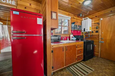 a red refrigerator in a kitchen with wooden walls at Highland Hideaway - Walk to lake and village! in Big Bear Lake