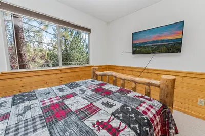 a bedroom with a quilt on a bed and two windows at Kubo Del Sol - DREAM LOCATION WITH HOT TUB! Beautiful, light and bright log cabin! in Big Bear Lake