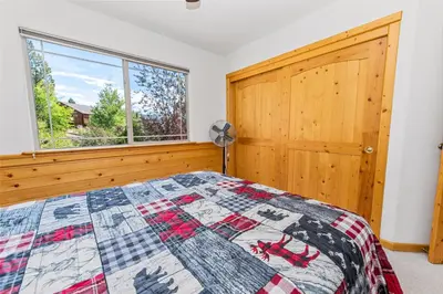 a bedroom with a quilt on a bed with a window at Kubo Del Sol - DREAM LOCATION WITH HOT TUB! Beautiful, light and bright log cabin! in Big Bear Lake