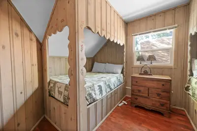 a bedroom with a bed in a room with wooden walls at Lake Cottage - Vintage Big Bear Cabin close to The Village and Lake in Big Bear Lake