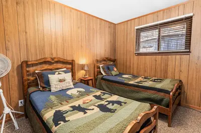 two beds in a room with wood paneled walls at Lakefront Retreat - Lakefront cabin near Holloways Marina in Big Bear Lake