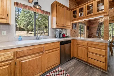 a kitchen with wooden cabinets and a sink and a window at Lakeview Haven - Large cabin with game room close to the lake! in Big Bear Lake